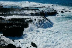 grande olas estrellarse en contra el rocas en el Oceano foto