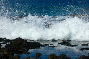 grande olas estrellarse en contra el rocas en el Oceano foto