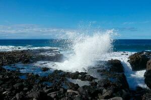 grande olas estrellarse en contra el rocas en el Oceano foto