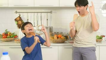 contento joven asiático padre y hijo haciendo desayuno juntos. juguetón en cocina a hogar foto
