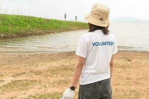 voluntarios desde el asiático juventud comunidad utilizando basura pantalones limpieza arriba naturaleza par foto