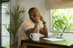 Estresante africano americano hombre trabajando en su hogar foto