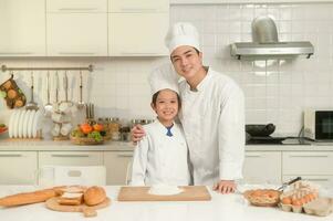 Young Asian father and his son wearing chef uniform baking together in kitchen at home photo