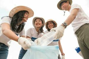 voluntarios desde el asiático juventud comunidad utilizando basura pantalones limpieza arriba naturaleza par foto