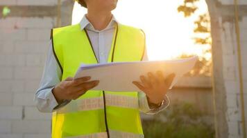 An Asian Engineering man wearing safety helmet analyzing construction drawings in construction site photo