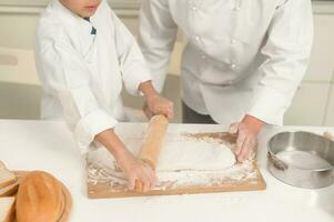 Young Asian father and his son wearing chef uniform baking together in kitchen at home photo