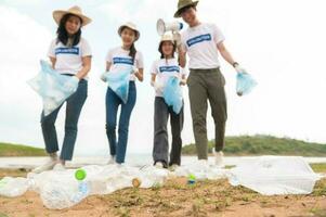 voluntarios desde el asiático juventud comunidad utilizando basura pantalones limpieza arriba naturaleza par foto