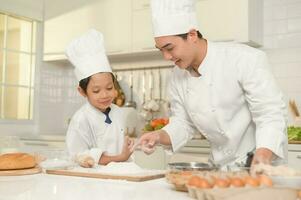 Young Asian father and his son wearing chef uniform baking together in kitchen at home photo