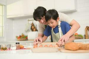 contento sonriente joven asiático padre y hijo Cocinando en cocina a hogar foto