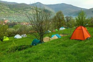 cámping carpas en un verde prado en el montañas en primavera. descanso con el tienda en naturaleza foto