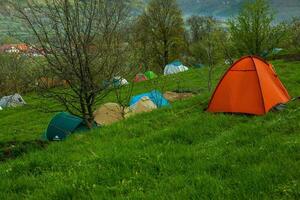 cámping carpas en un verde prado en el montañas en primavera. descanso con el tienda en naturaleza foto