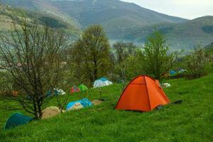 Camping tents on a green meadow in the mountains in spring. Rest with the tent in nature photo