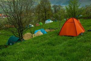 cámping carpas en un verde prado en el montañas en primavera. descanso con el tienda en naturaleza foto