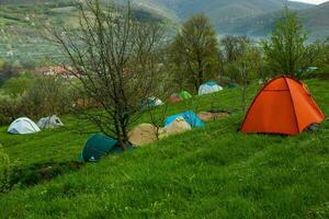 cámping carpas en un verde prado en el montañas en primavera. descanso con el tienda en naturaleza foto