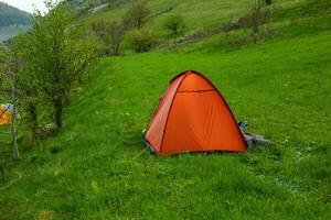 Camping tents on a green meadow in the mountains in spring. Rest with the tent in nature photo