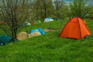 cámping carpas en un verde prado en el montañas en primavera. descanso con el tienda en naturaleza foto