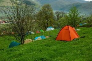 cámping carpas en un verde prado en el montañas en primavera. descanso con el tienda en naturaleza foto