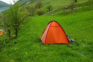 Camping tents on a green meadow in the mountains in spring. Rest with the tent in nature photo