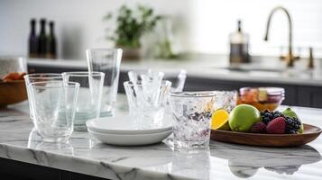 Different clean dishware and glasses on white marble table in kitchen, photo