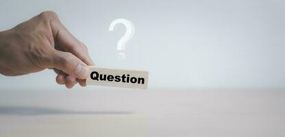 Hand hold Wooden cube block in question mark mean what on cement table background, column of wooden blocks with question sign mark. copy space,FAQ frequently asked questions, Answer, Information photo