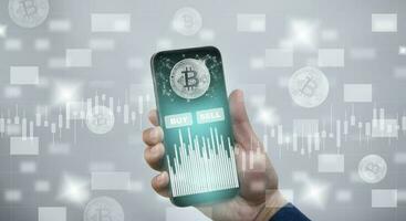 Smartphone with Bitcoin chart on-screen among piles of Bitcoin concept. businessman touch on mobile app screen with big BUY and SELL buttons on the stock market, Cryptocurrency and finance. photo