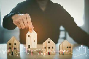 Man hand choosing mini wood house model from model on wood table, Planning buy Real Estate, Planning to buy property. concept of Choose the best. photo