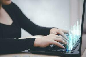 Businesswoman are using computers to work at home. Technology and Business trend analysis concepts, with business graphs coming out on the computer notebook. photo