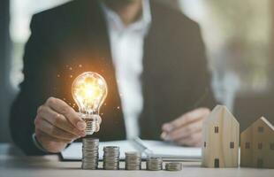 Businessman hand holding light bulb with line connect and Coins stack on the wooden table, Saving ideas and investment budget, Creative ideas concept of saving money  concept, Copy space photo