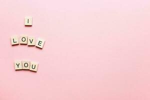 Design I love you made of wooden letters on a pink background. Flatly i love you. Flat lay valentines day photo