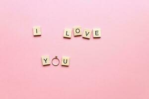 I love you made of wooden letters on a pink background. Marry me. Engagement ring. Postcard I love you photo