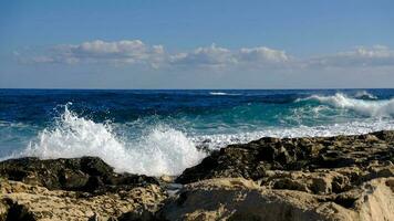 azul mar ola y blanco espuma y chapoteo. Roca playa en isla de Malta, No arenoso playa. verano fiesta frontera marco concepto. tropical isla vacaciones fondo. turista viaje bandera diseño modelo. foto