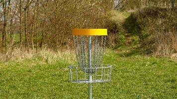 Disc Golf basket. Frisbee golf is sport and hobbie in outdoor park. Metal basket with chains for disc game surrounded by vibrant green trees. photo