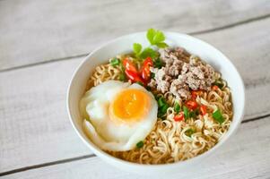 instant noodles cooking tasty eating with bowl - noodle soup, noodles bowl with boiled egg minced pork vegetable spring onion lemon lime lettuce celery and chili on table food photo