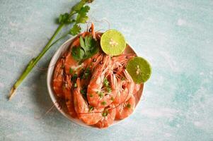 Fresh shrimps prawns seafood lemon lime with herbs and spice, shrimp on white bolw and wooden background dining table food photo