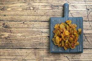 Dried raisins from white grapes on a wooden chopping board. photo