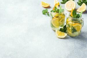 Lemonade drink of soda water, lemon and mint leaves in jar on light background. Copy space photo