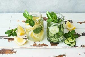 Detox water for healthy lifestyle. Fresh water in jar with lemon, cucumber and mint on wooden table. photo