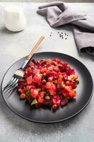 Vinaigrette with beetroot and boiled vegetables, traditional Russian homemade salad. A black plate on a light background. photo