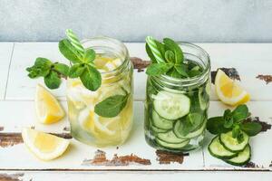 Detox water for healthy lifestyle. Fresh water in jar with lemon, cucumber and mint on wooden table. photo