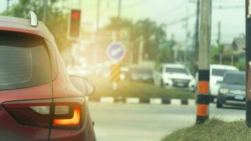 Abstract and blurred rear side of red car stop by traffic red light control. Car open trun on brack light. Cars across the street queue to drive forward. Environment of trees and country in Thailand. photo