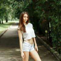 Slim sexy woman in shirt and shorts standing in the park. photo