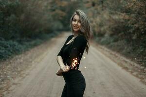 Beautiful young girl holding a sparkler in the park. photo