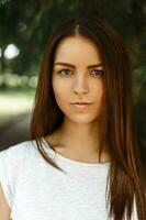 Portrait of a beautiful young girl on a background of green summer park photo