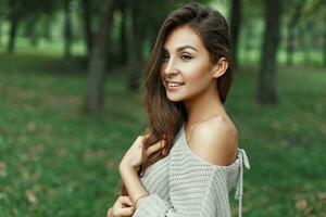 Pretty young girl in a gray sweater in the park photo