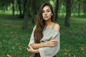 Beautiful model woman in vintage knitted sweater with naked shoulders in the park looking at the camera photo