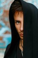 Portrait of a handsome man in a black hood. Hidden face. photo