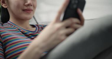 Slow motion dolly shot, Close up Young pretty woman to resting, she sitting, smile and use smartphone to chatting on comfortable sofa in living room at home video