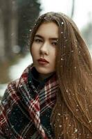 Beautiful young woman with a trendy scarf outdoors in snowy weather photo