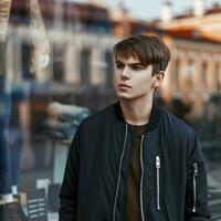 Handsome young man in stylish black jacket shopping near a showcase photo