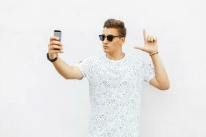 Handsome man playing a game in the smartphone. Guy makes selfie photo